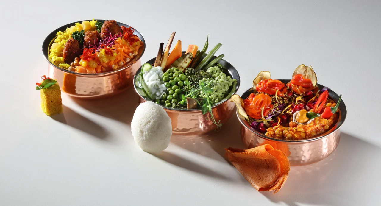 Three small copper dishes representing the three doshas, filled with vibrant food.
