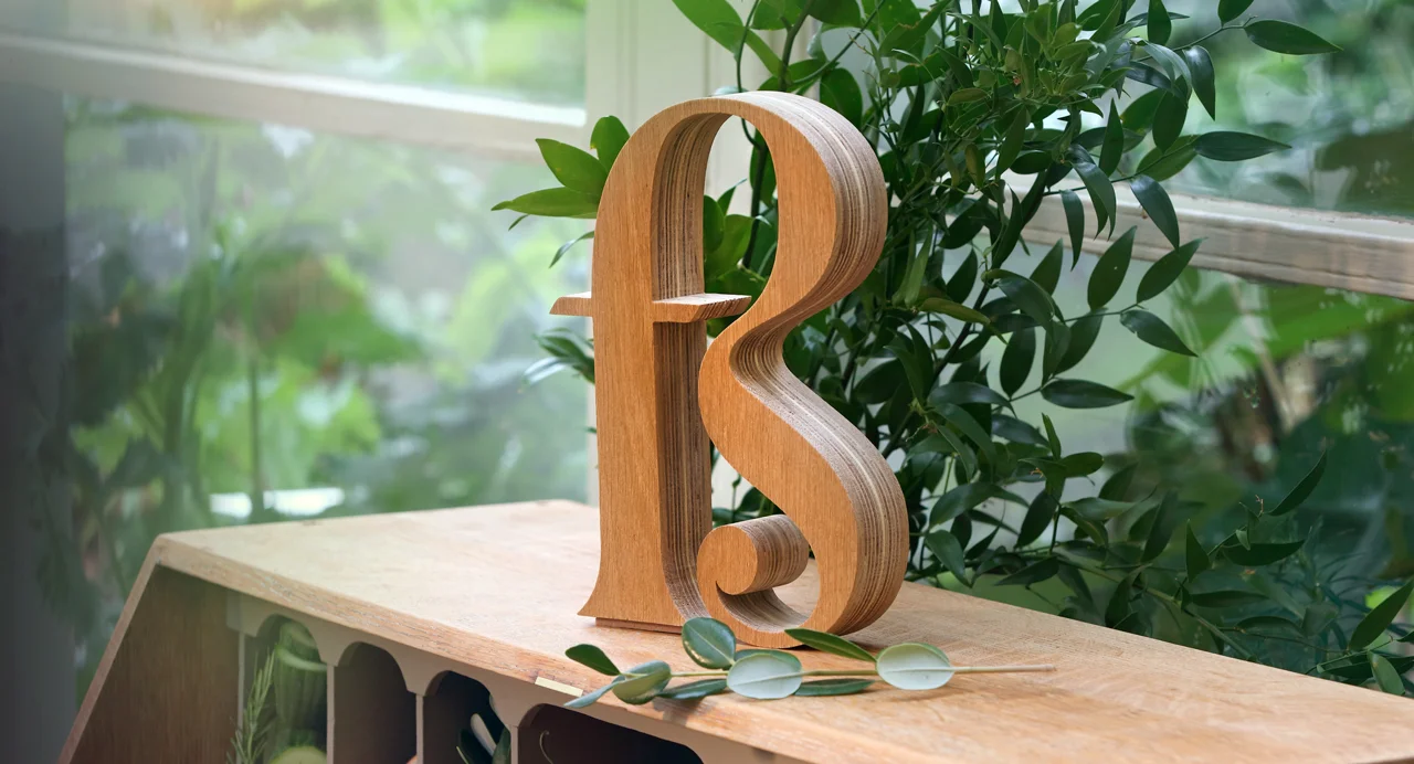 Wooden Free Spirit logo, sitting on top of a bureau with greenery.