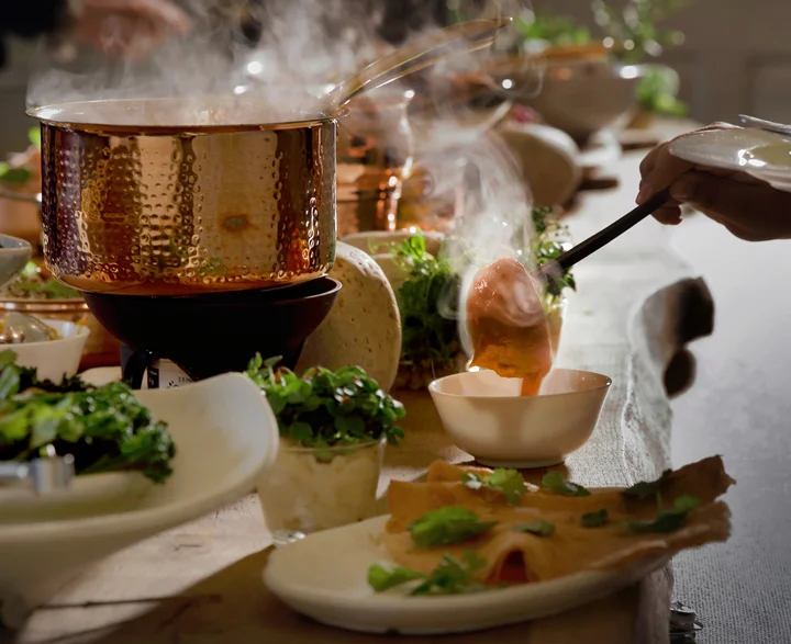 Soup being poured into a small bowl, styled with natural textures.